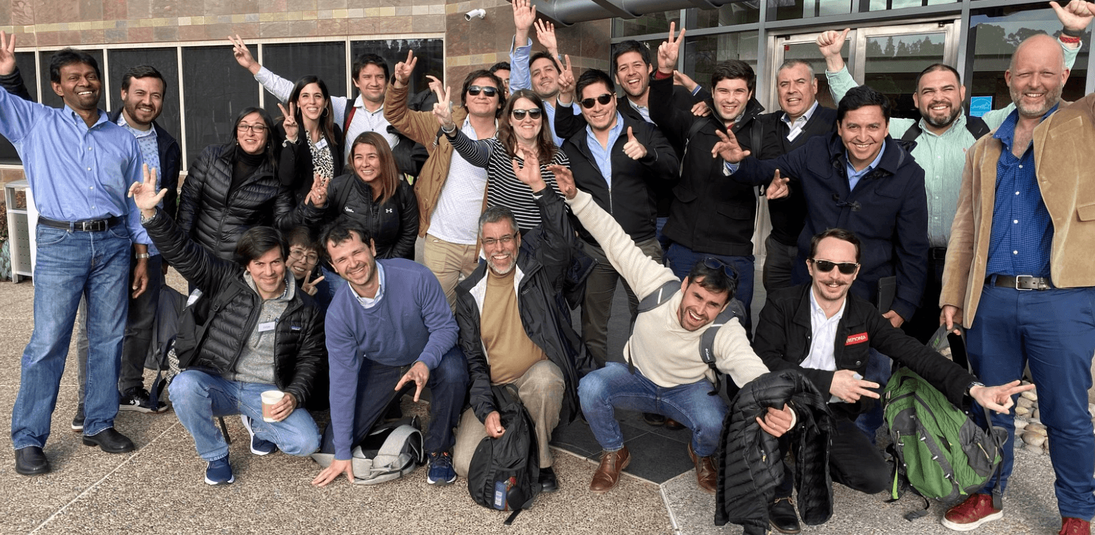 A Latin American programme cohort outside a venue, arms raised.